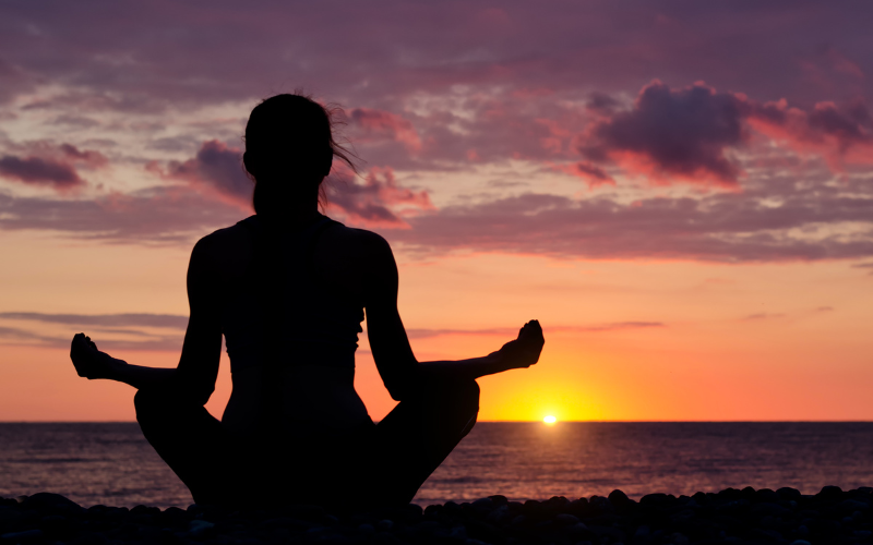 A person meditating on a mountaintop at sunrise, with a glowing light symbolizing the power to influence reality.