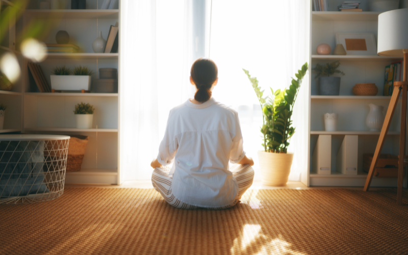 A serene individual meditating in a quiet room with light streaming through a window to influence reality