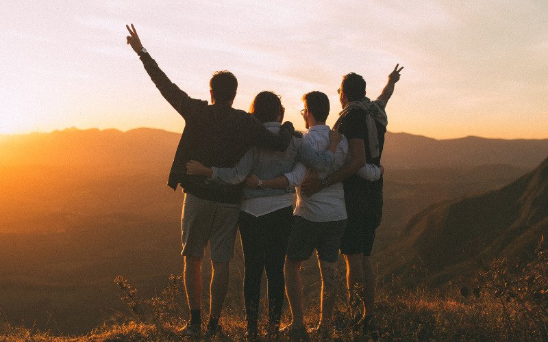 A group of friends laughing together during a picnic in a lush green park, representing social connections in The Holistic Guide to Wellness.