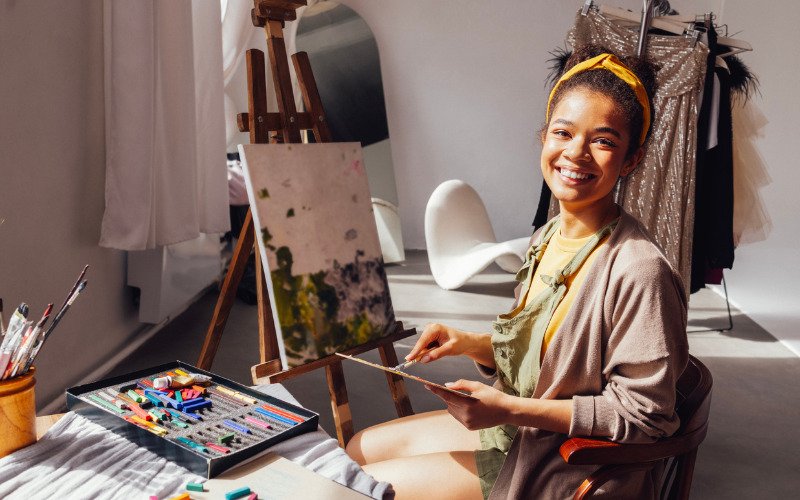 An artist painting on a vibrant canvas in a sunlit studio, demonstrating creative outlets in The Holistic Guide to Wellness.